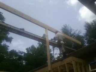 Carpenter setting a ridge beam over a new addition frame — Ice Dam Removal by Roofing Brothers in Saint Matthews
