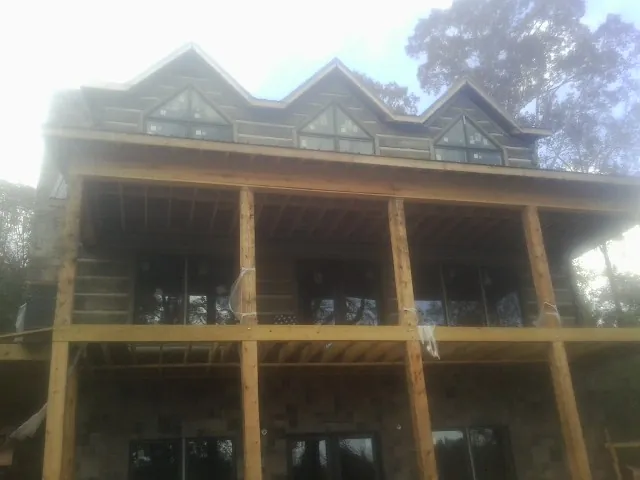 Dormers and porch framing on a large log home under construction — Roof Coating work by our crew in Saint Matthews