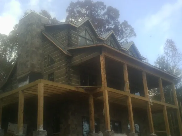 Stone chimney and dormers on a large log home with a timber porch in Saint Matthews