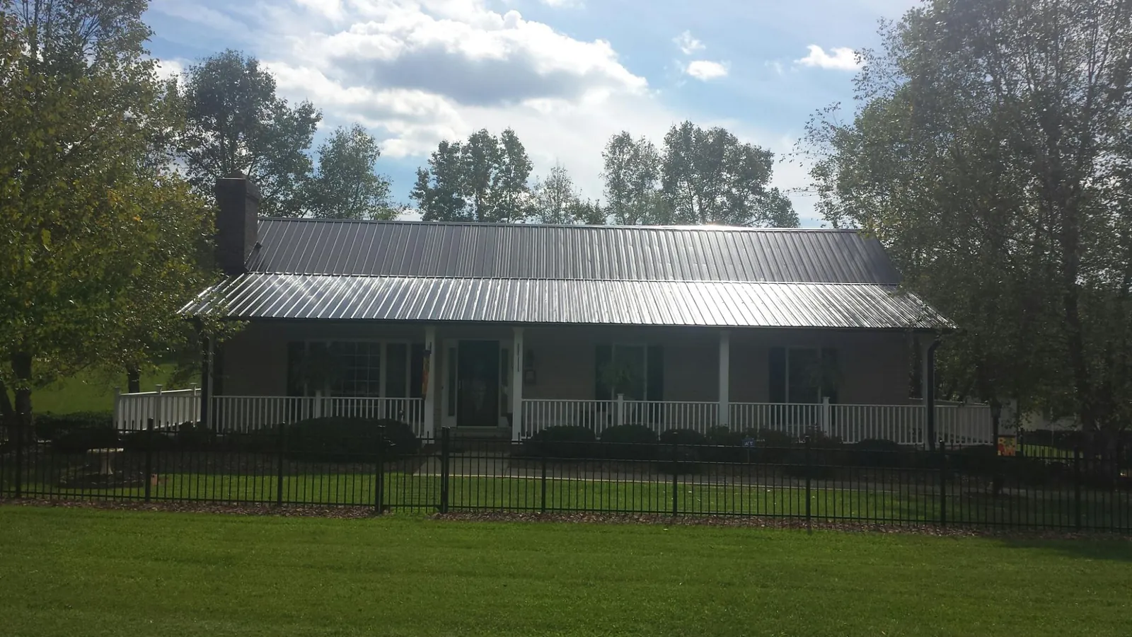 Gray metal roof on a brick ranch with a full width front porch — Gutter Guard Installation work by our crew in Saint Matthews