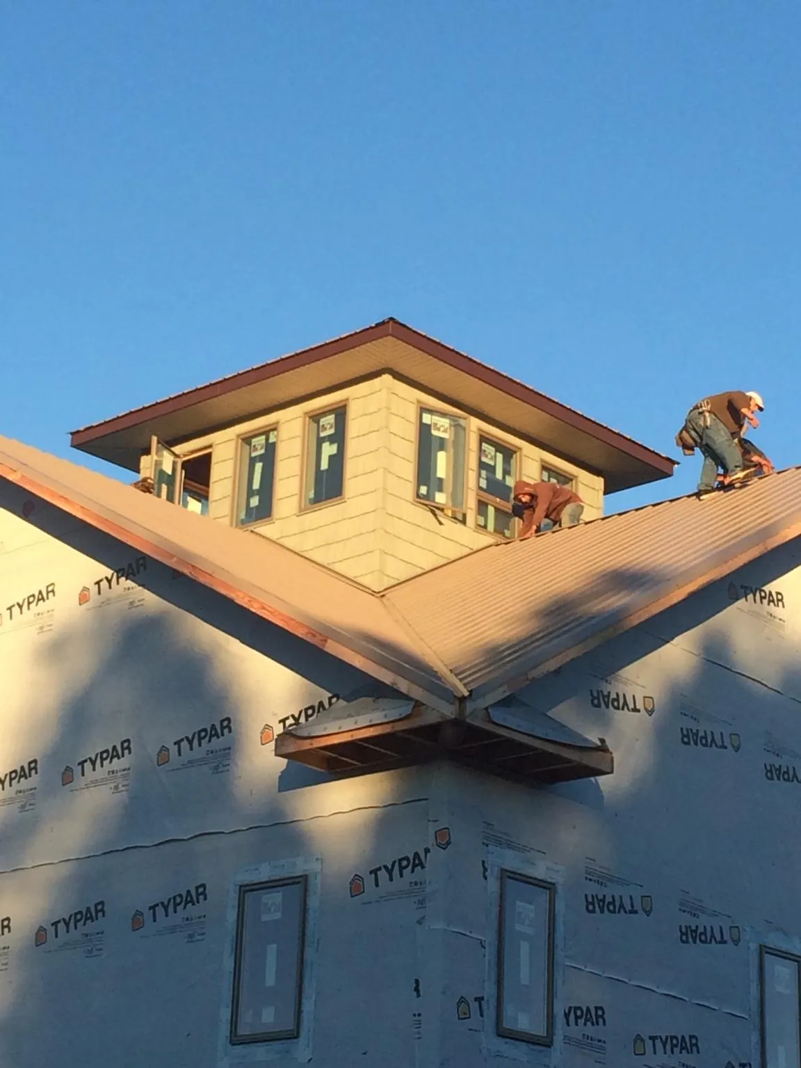 Roofers working around a rooftop cupola on a new metal roof at sunset — Roof Waterproofing in Saint Matthews by Roofing Brothers